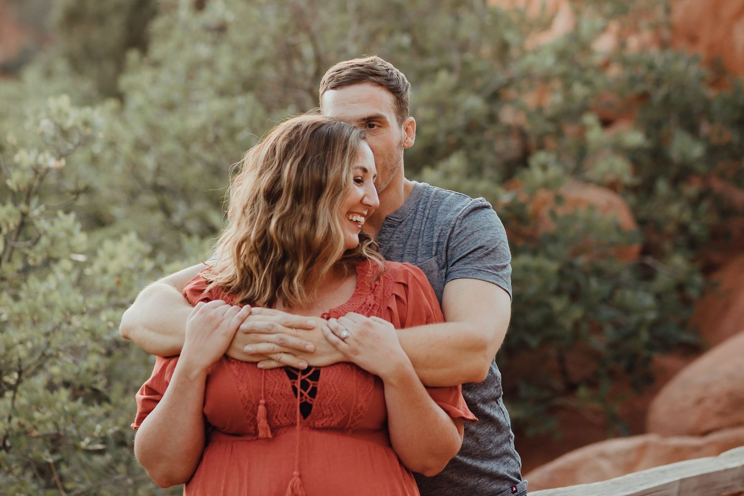 A couple shares an intimate moment while standing in front of red rock formations.