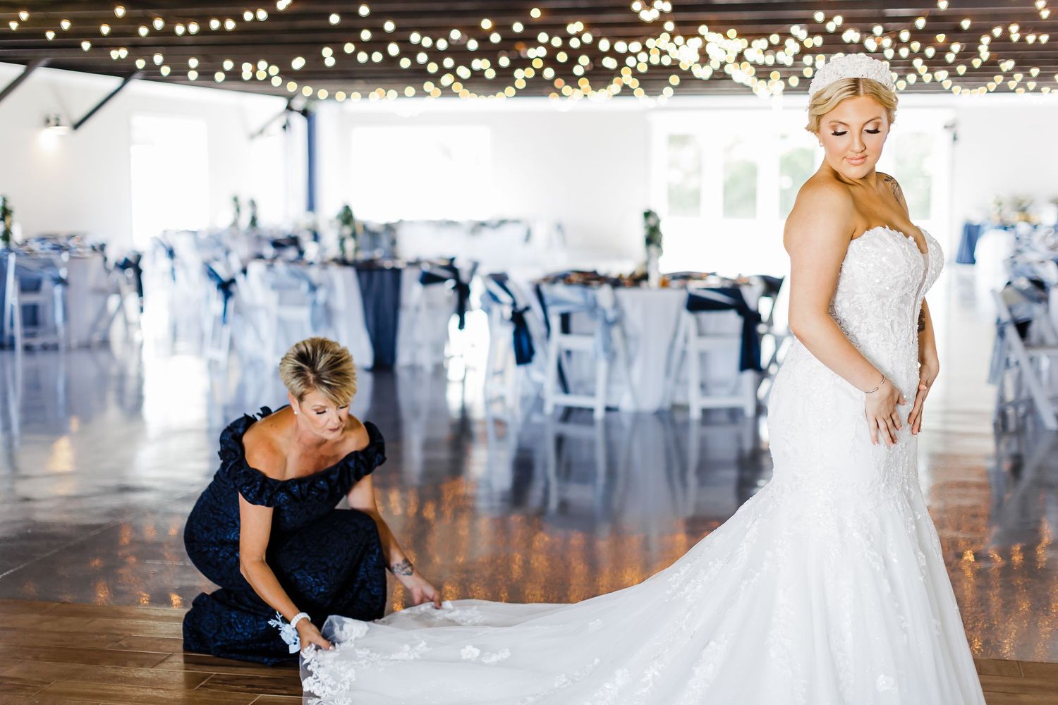 Final dress adjustments being made in a light-filled reception venue.