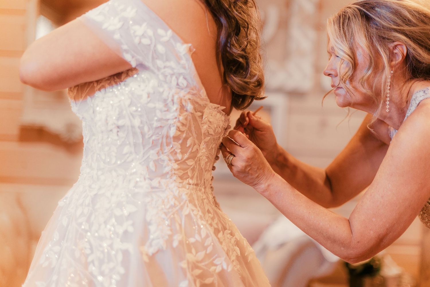 Close-up detail of intricate lace wedding dress during preparation.