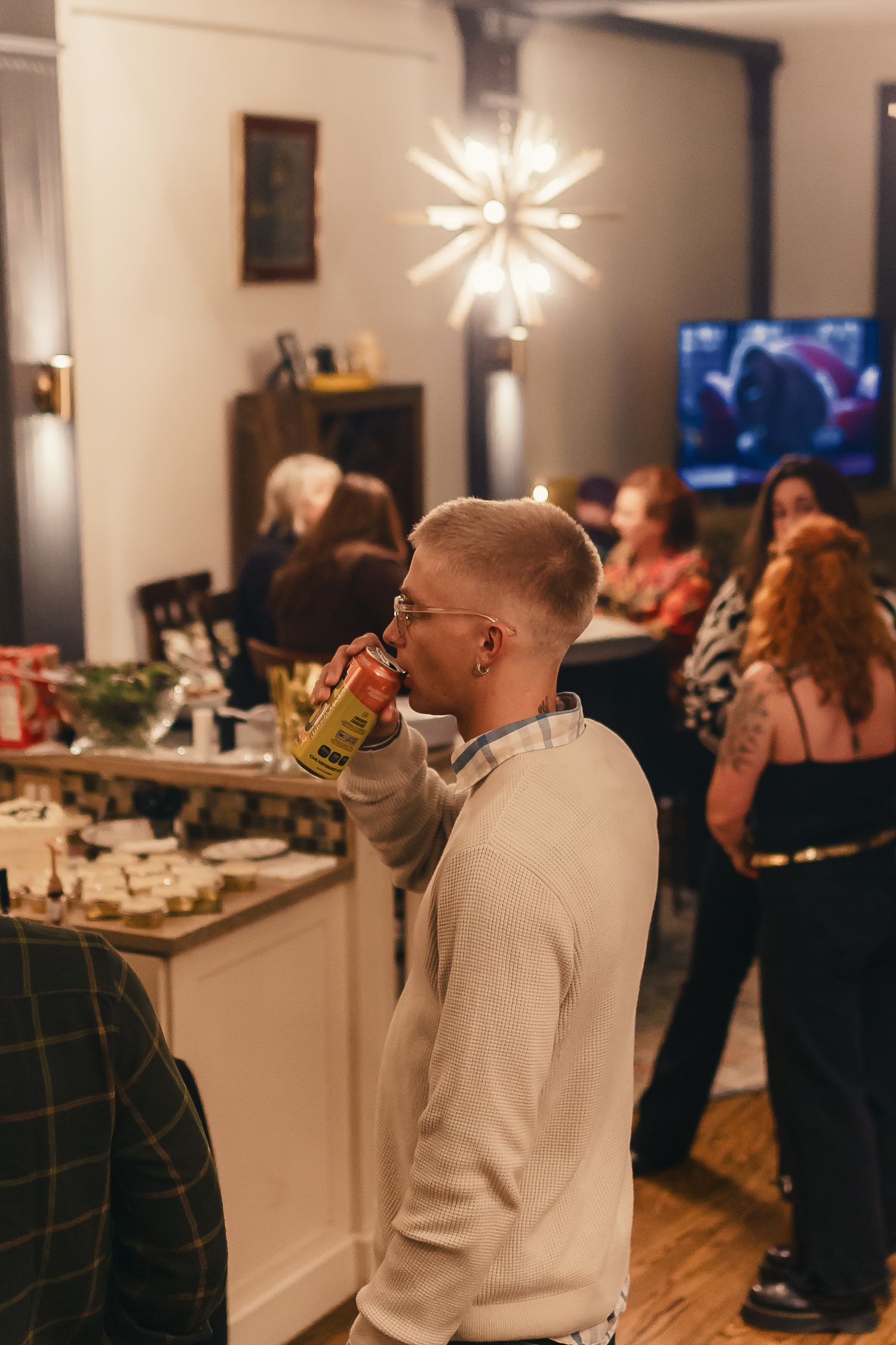 A casual social gathering in a modern living room with star-shaped pendant lights and white decor.