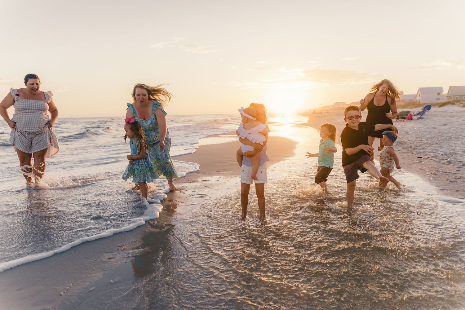Group playing and splashing in shallow ocean water during sunset.