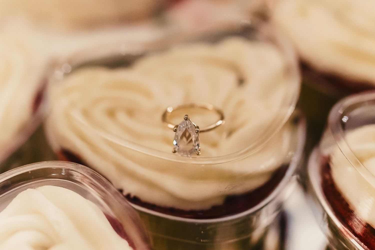 Elegant engagement ring photographed on cream-colored cupcake frosting.