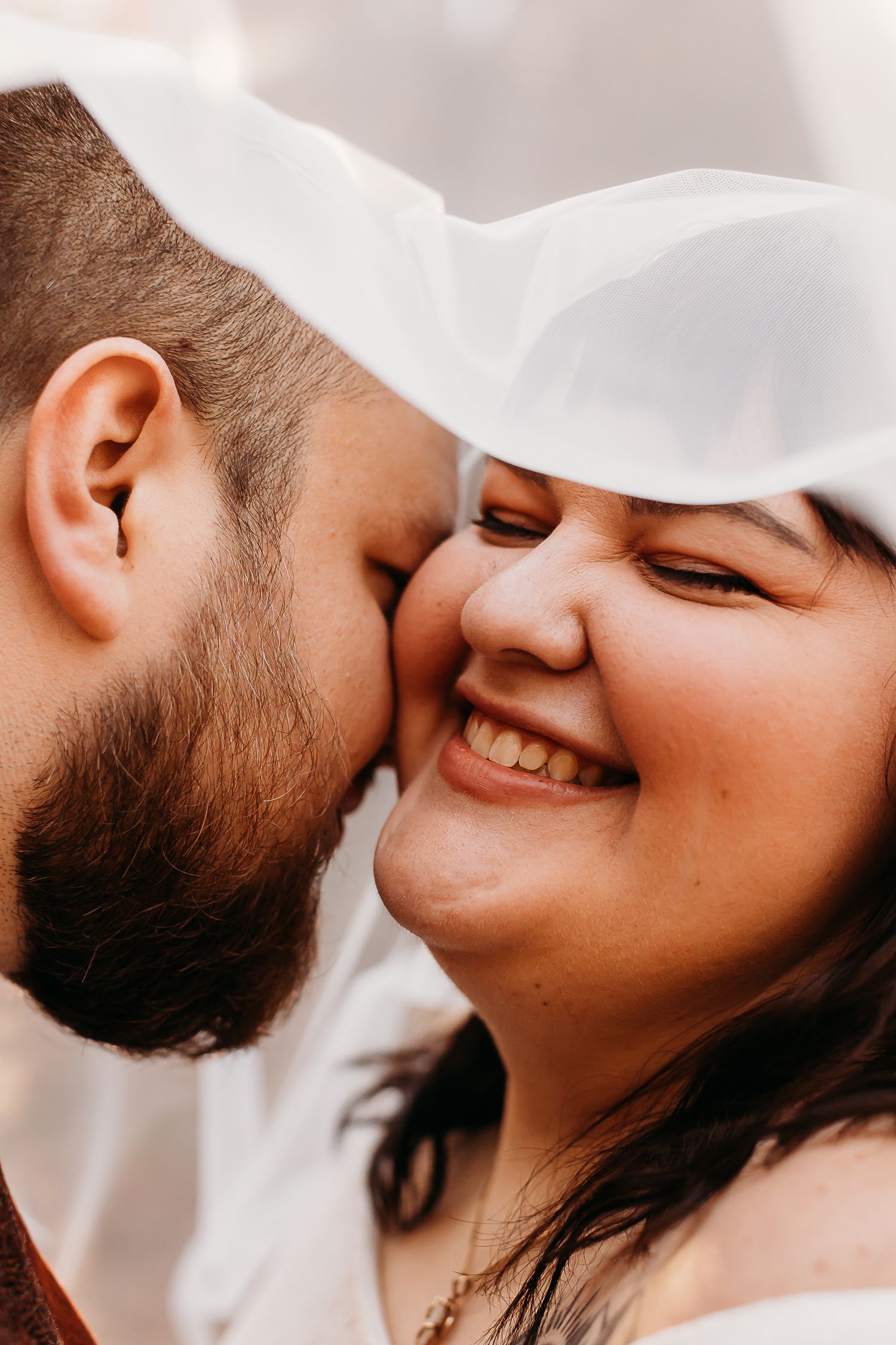Intimate close up portrait of couple sharing tender moment in white attire.