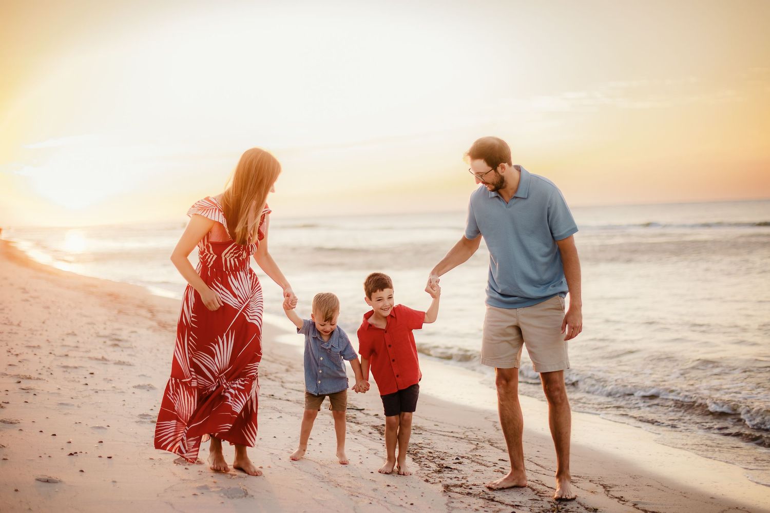 Family walking together along beach at sunset.