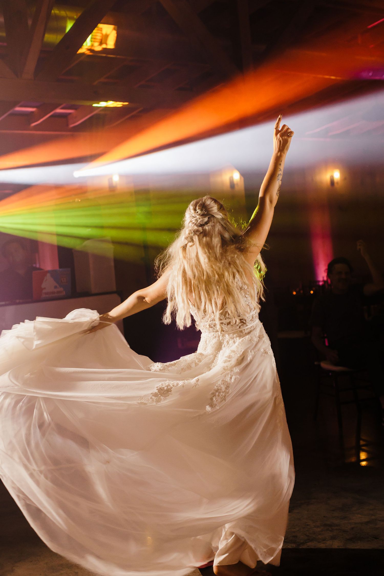 Flowing white dress twirls dramatically under colorful dance floor lighting.