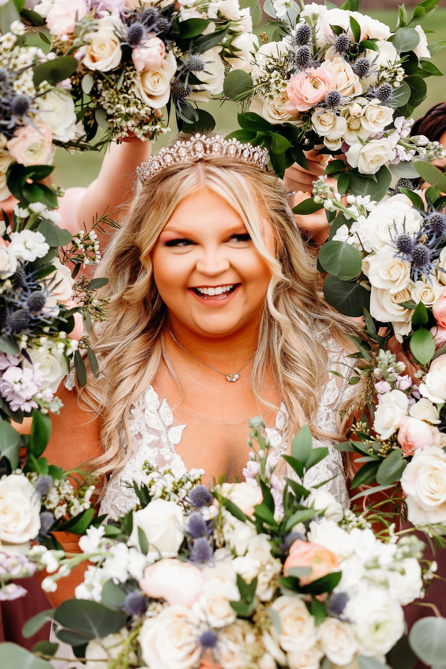 Bride wearing tiara poses with romantic floral crown and roses.