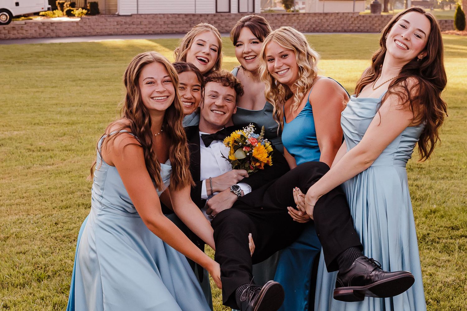 Bridal party poses playfully outdoors in light blue dresses.