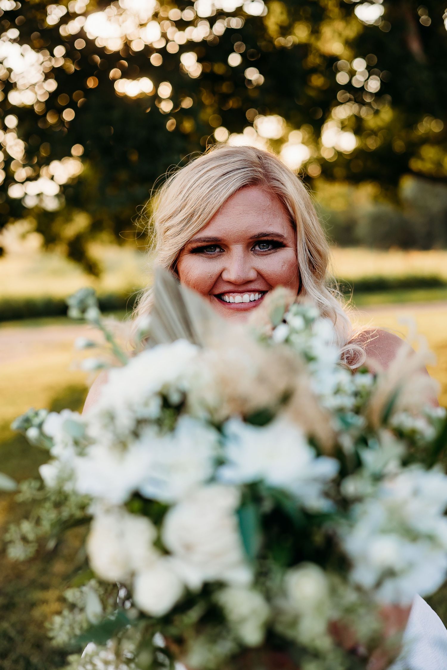 Beautiful bridal bouquet with white flowers and greenery in golden sunlight.