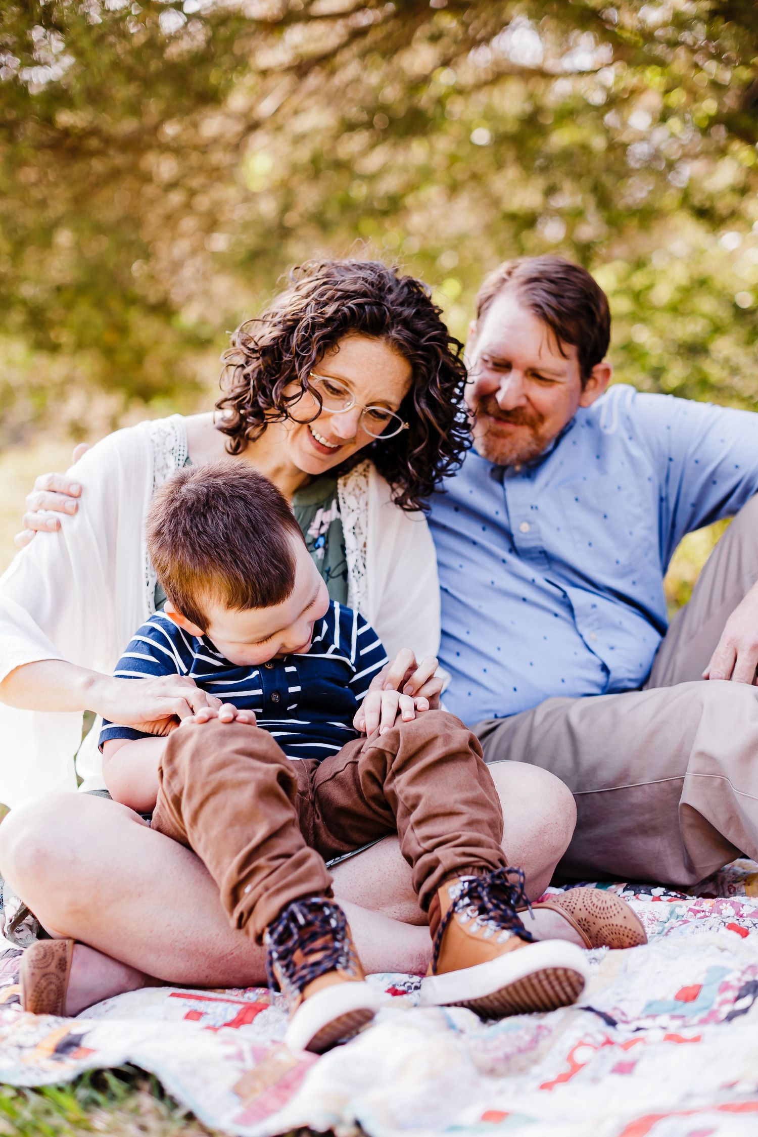 A family relaxing together on a blanket outdoors during a sunny afternoon.