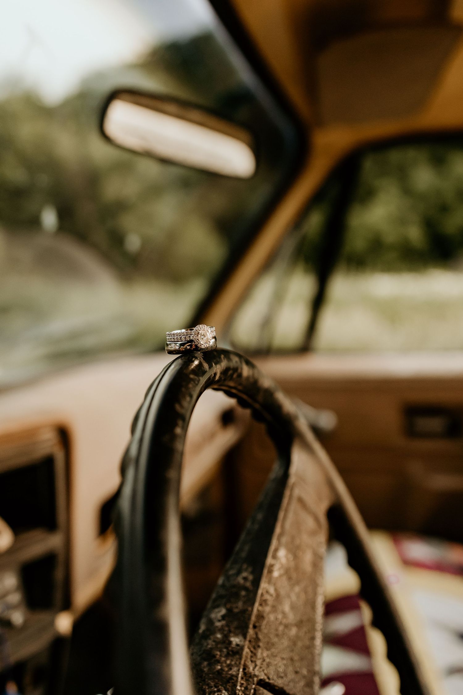 Wedding ring detail shot on vintage car steering wheel with bokeh background.