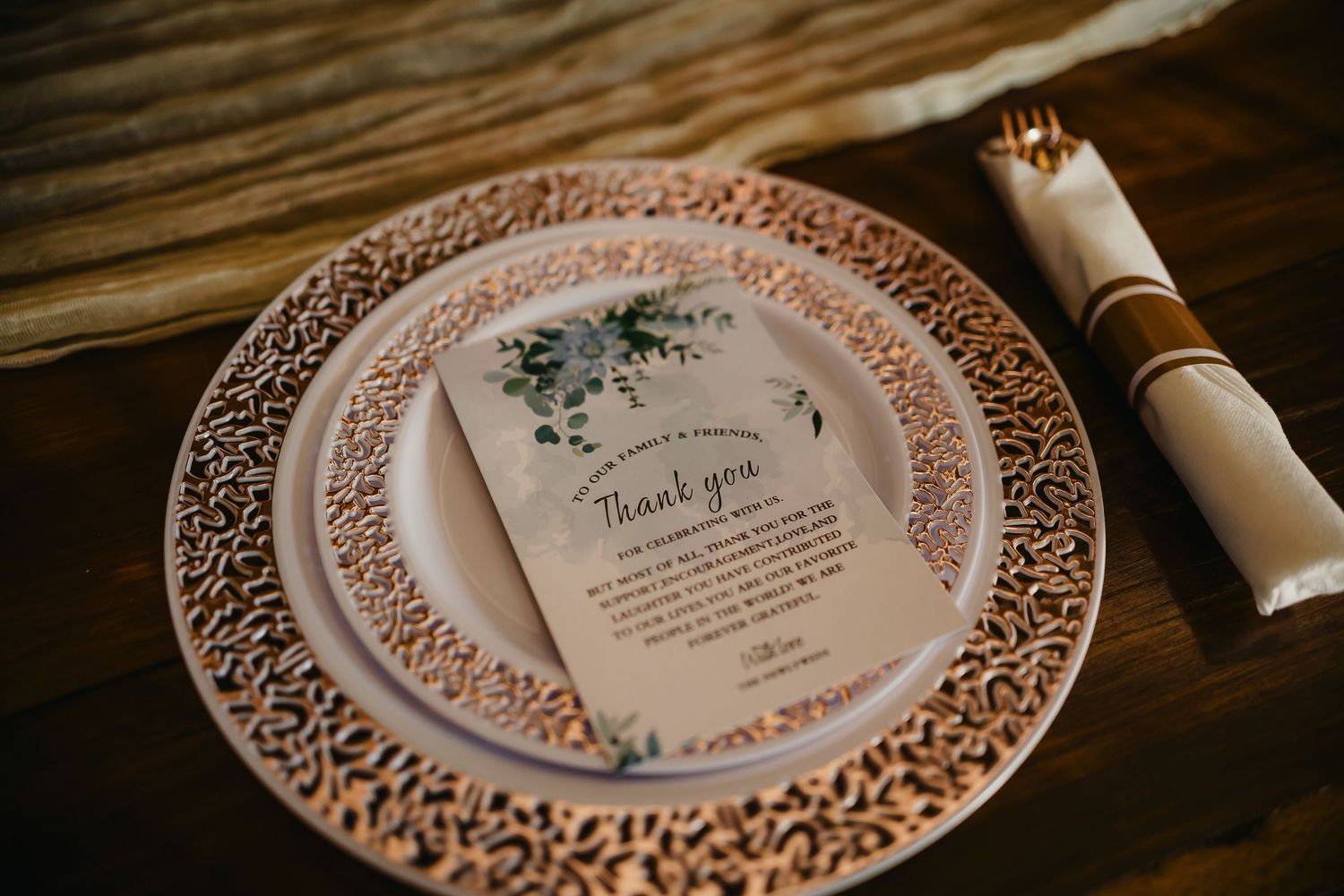 Elegant wedding place setting with ornate rose gold charger plate and thank you note.