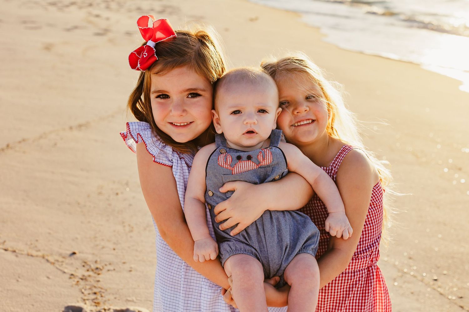 Family posing together on sandy beach during golden hour photoshoot.