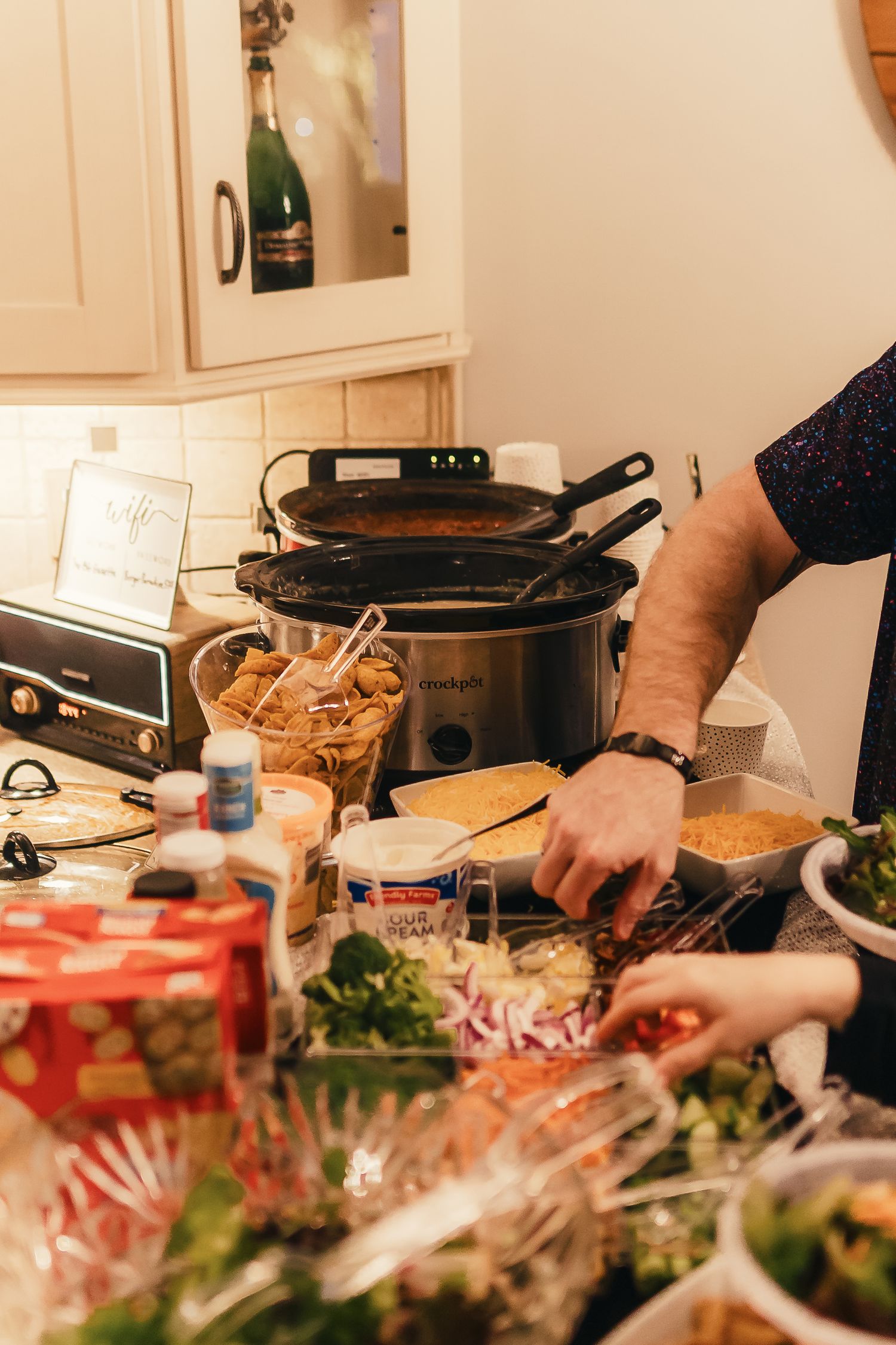 A buffet spread of party food and appetizers with slow cookers and various dishes laid out on a counter.