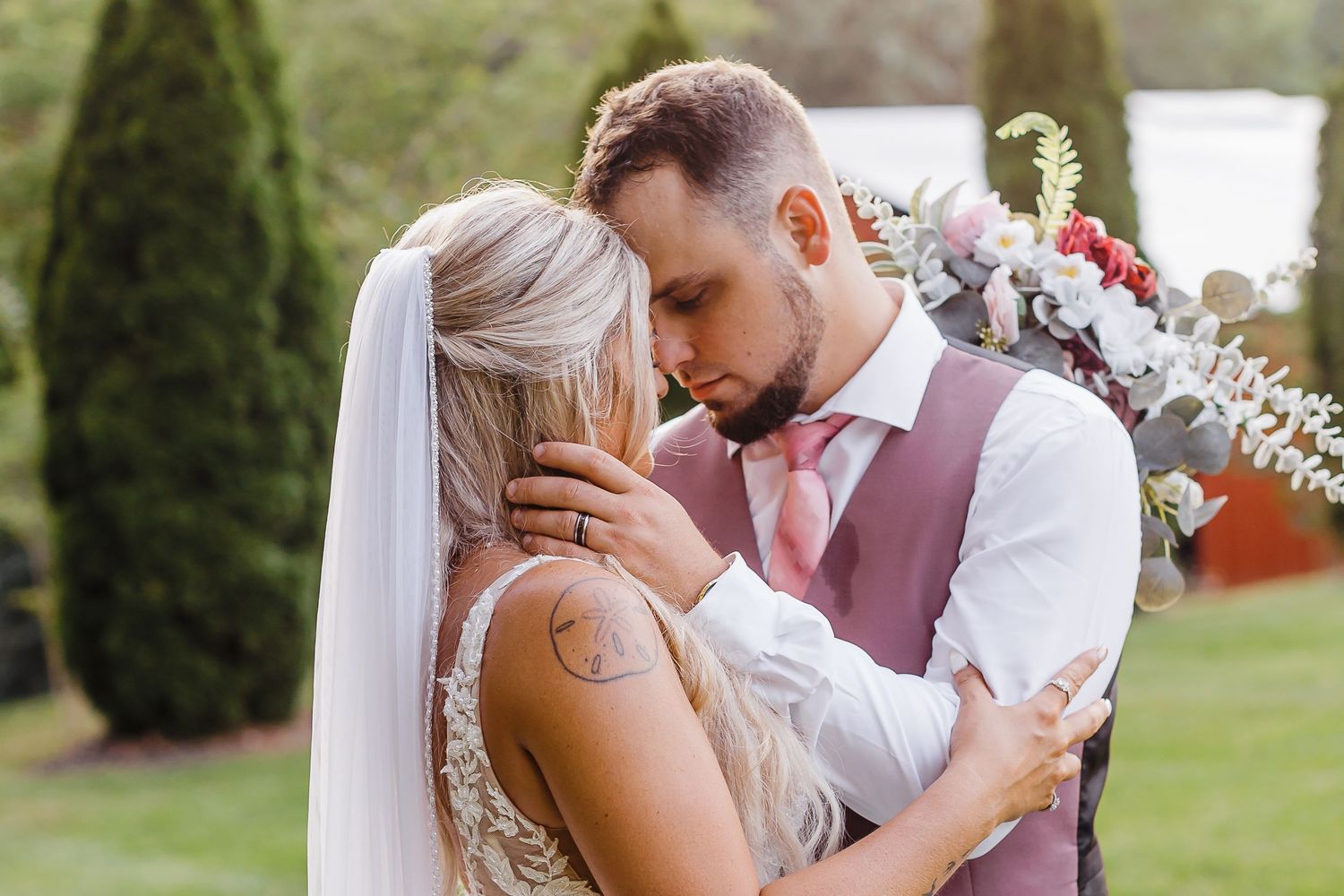 A tender moment between newlyweds in an outdoor garden setting.