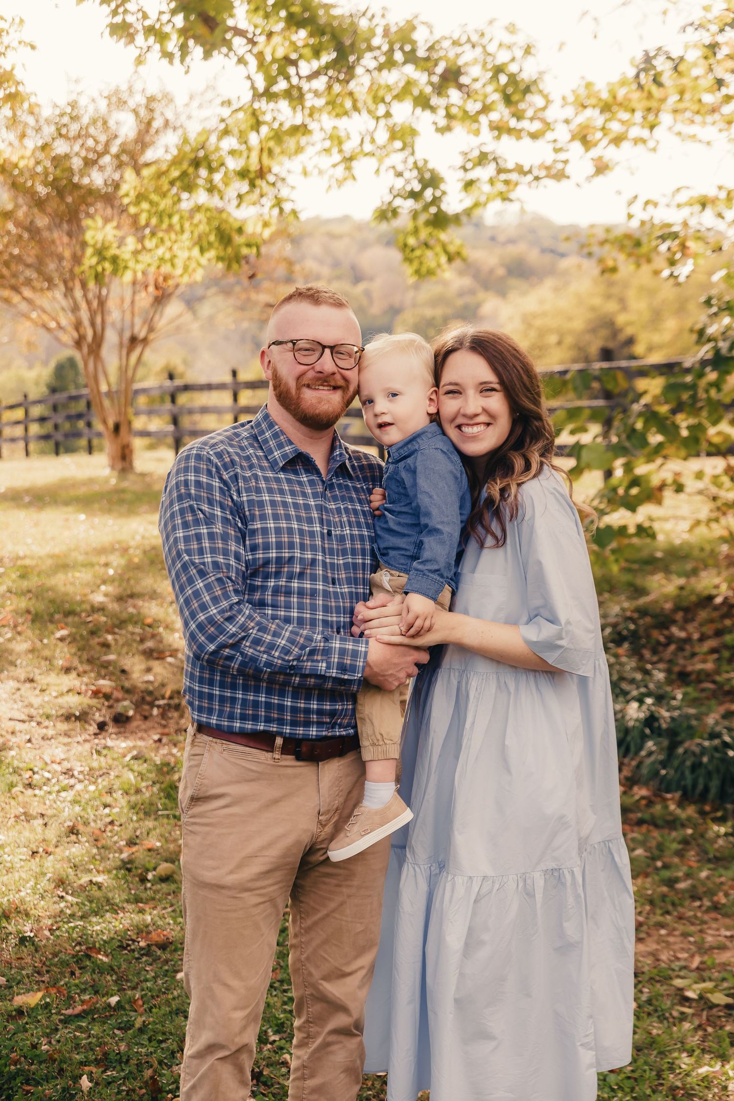 A family shares a joyful moment together outdoors during golden hour with autumn trees in the background.