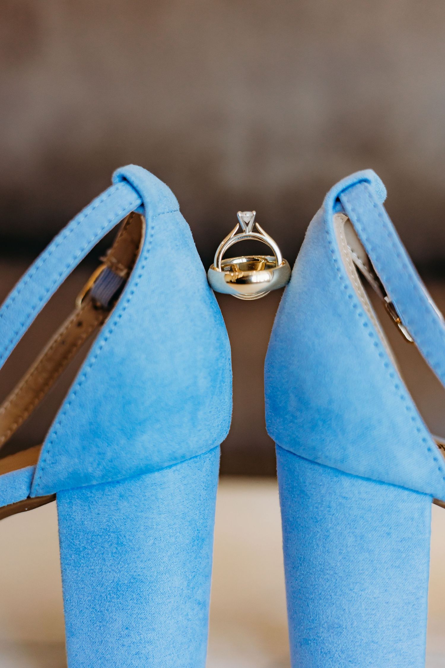 Wedding rings balanced on bright blue textured surface creating artistic detail shot.