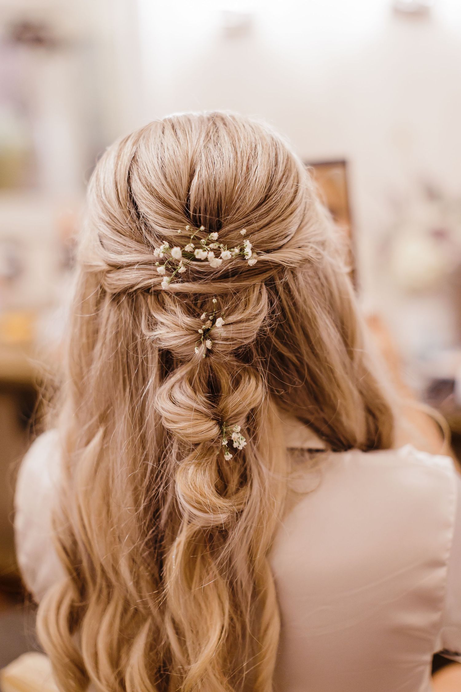 Delicate floral hair accessories arranged in an elegant half-up bridal hairstyle with soft waves.