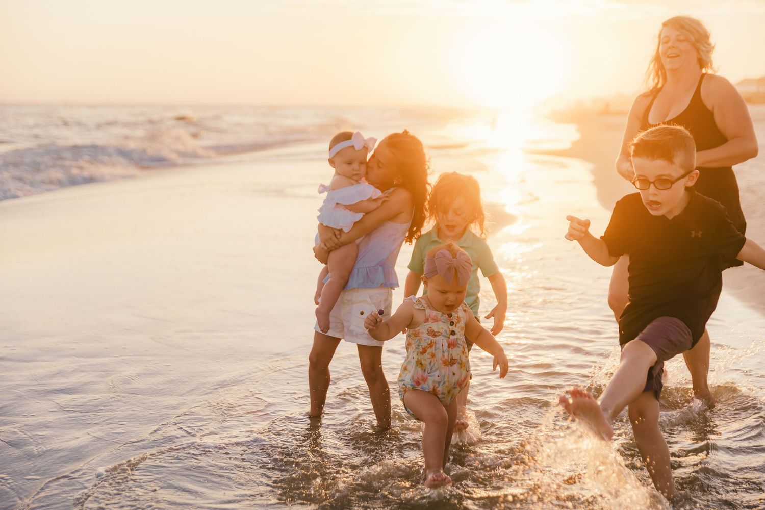 Family enjoying sunset beach time while playing in ocean waves.
