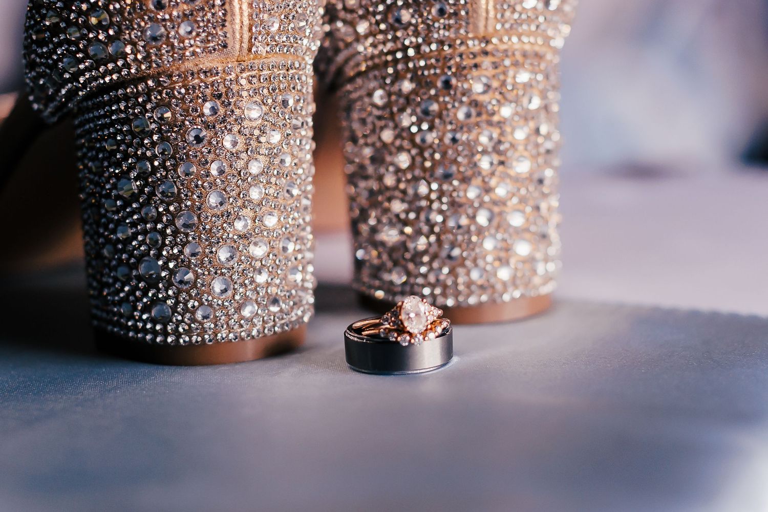 Close-up of sparkly wedding heels with wedding rings placed between them.
