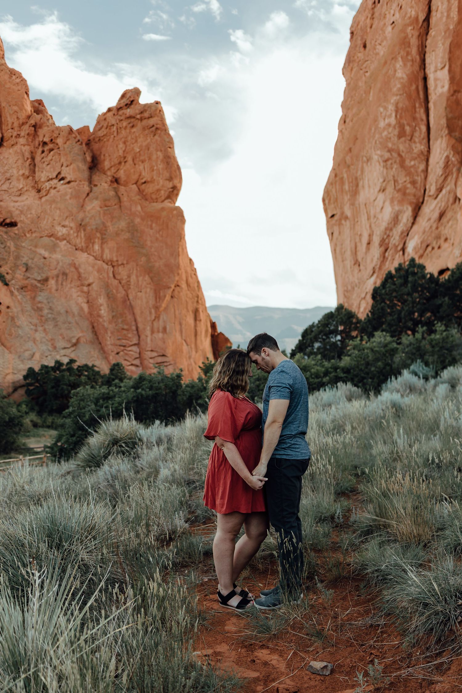Couple sharing intimate moment among red rock formations in desert landscape.