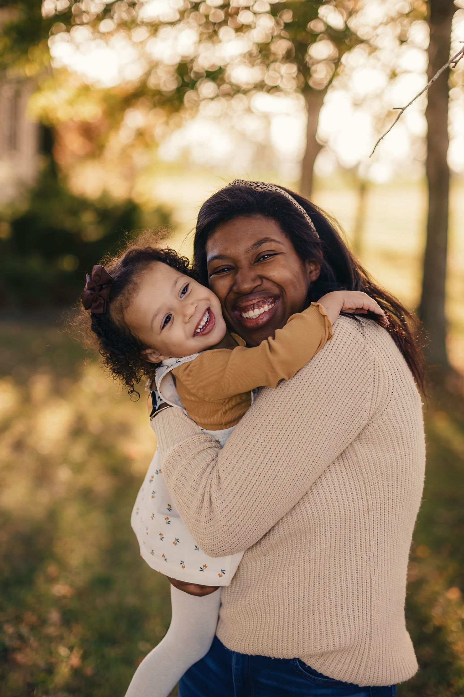 Mother and child sharing joyful hugs and laughter in warm autumn sunlight.