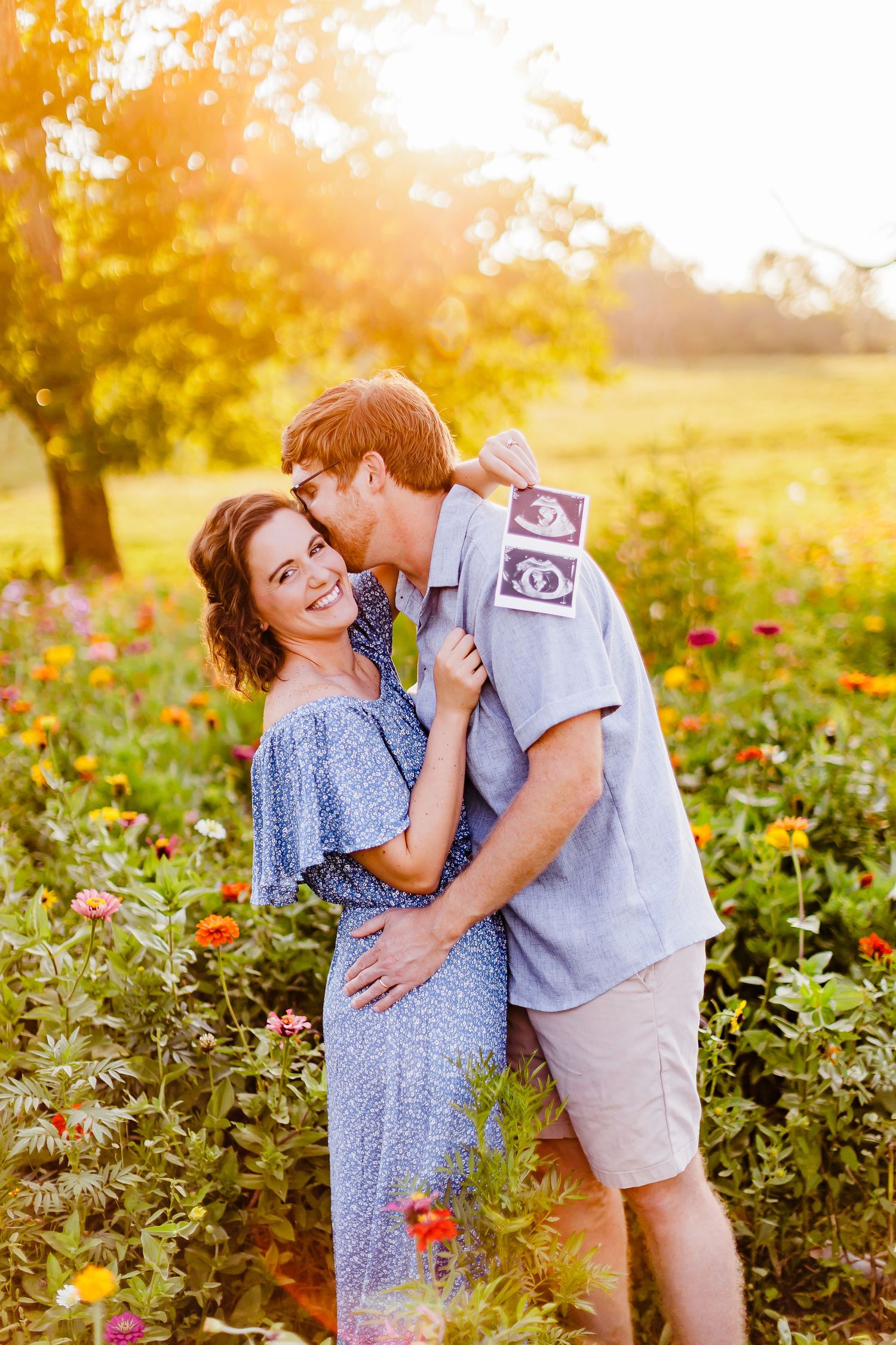 Couple embracing in a sunlit field of wildflowers during golden hour.