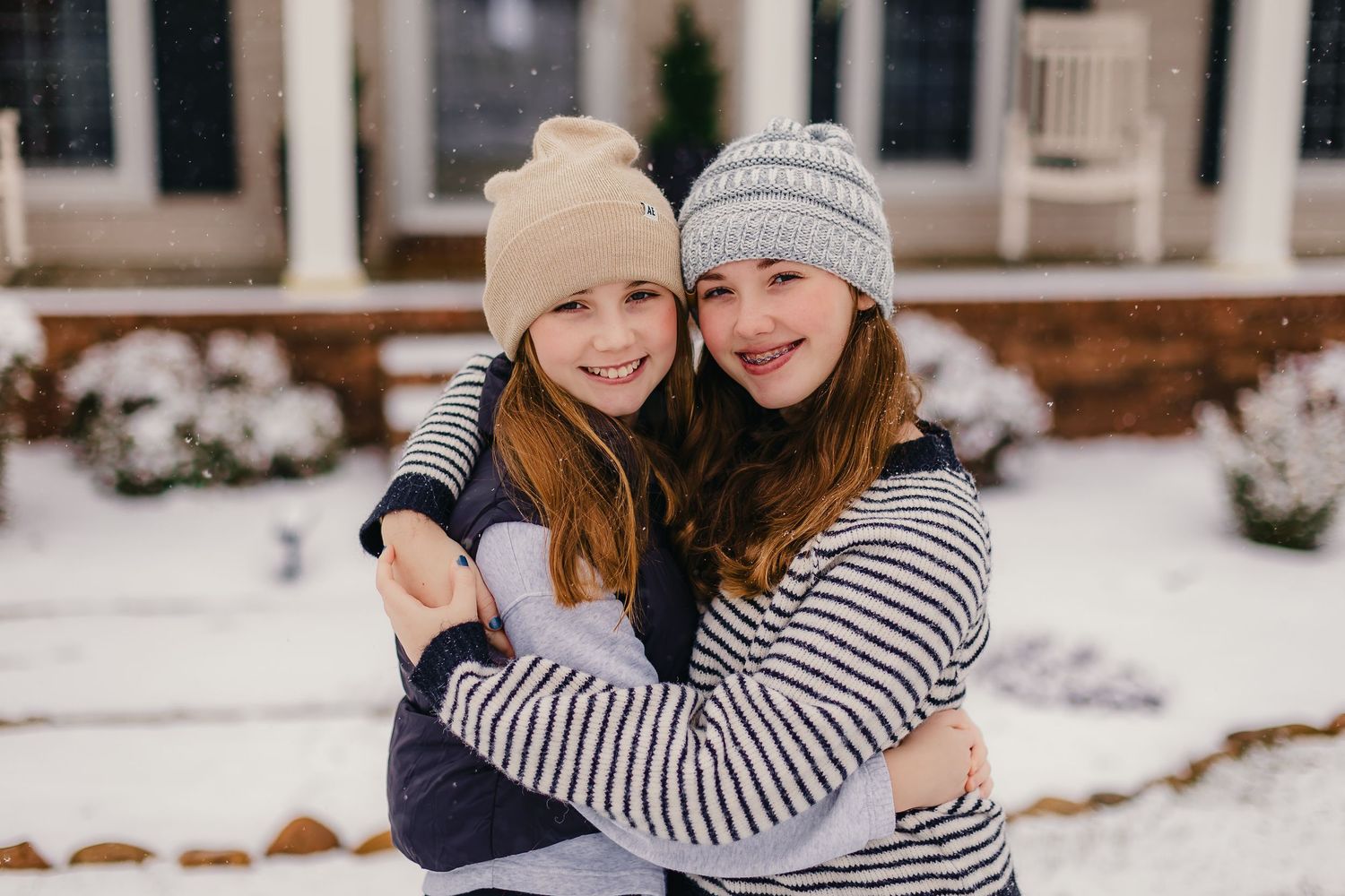 Two people share a warm embrace while wearing winter hats in snowy weather.