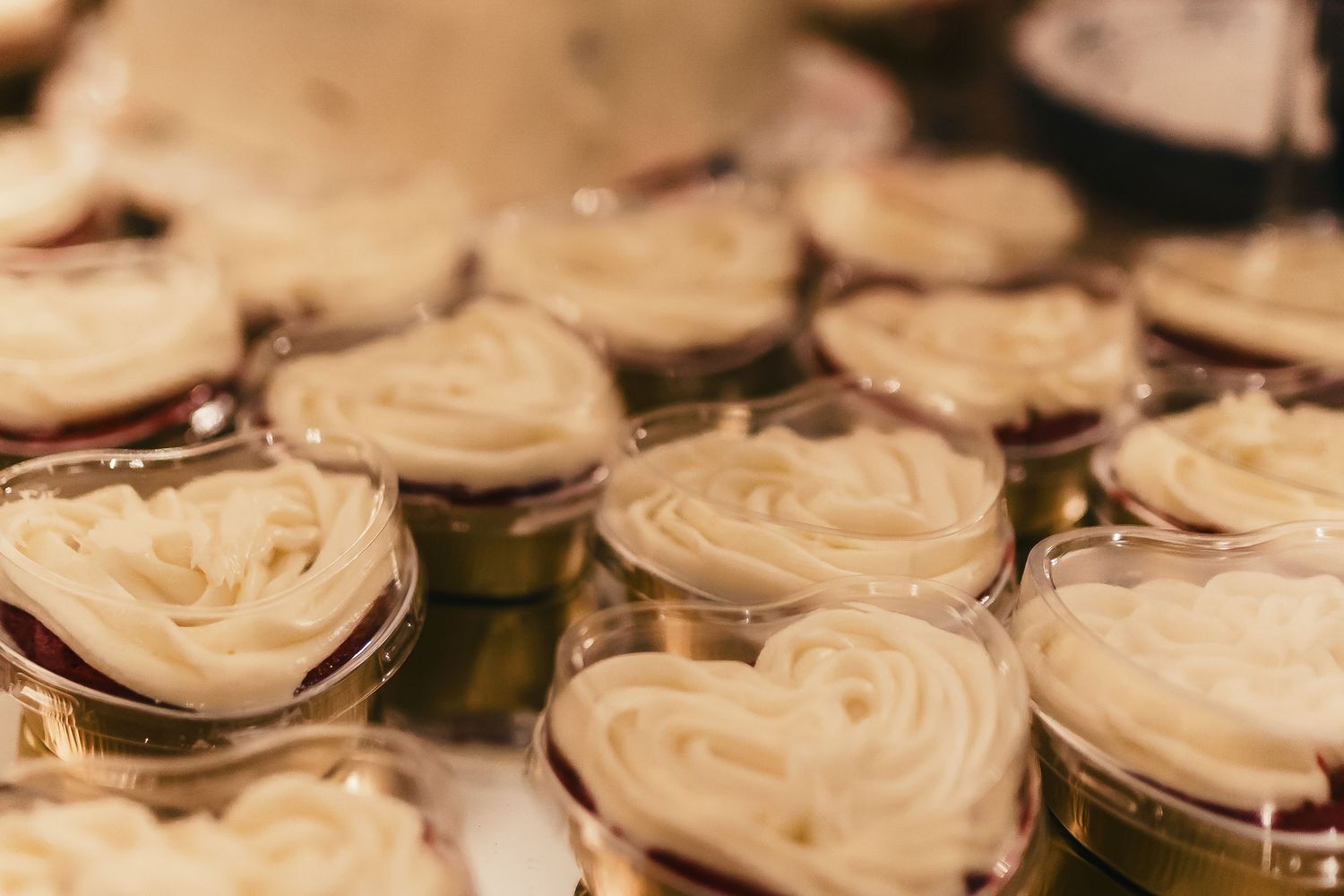 Close-up view of heart-shaped cupcakes with swirled cream frosting arranged in rows.