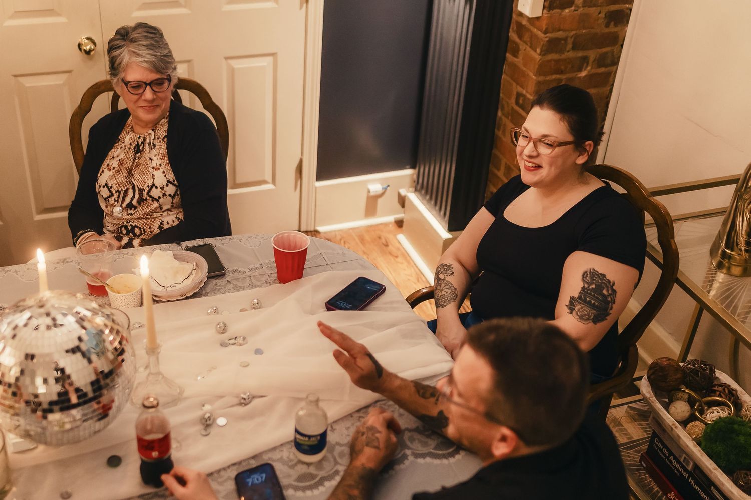 People seated at a long table engage in conversation during what appears to be a holiday dinner gathering.