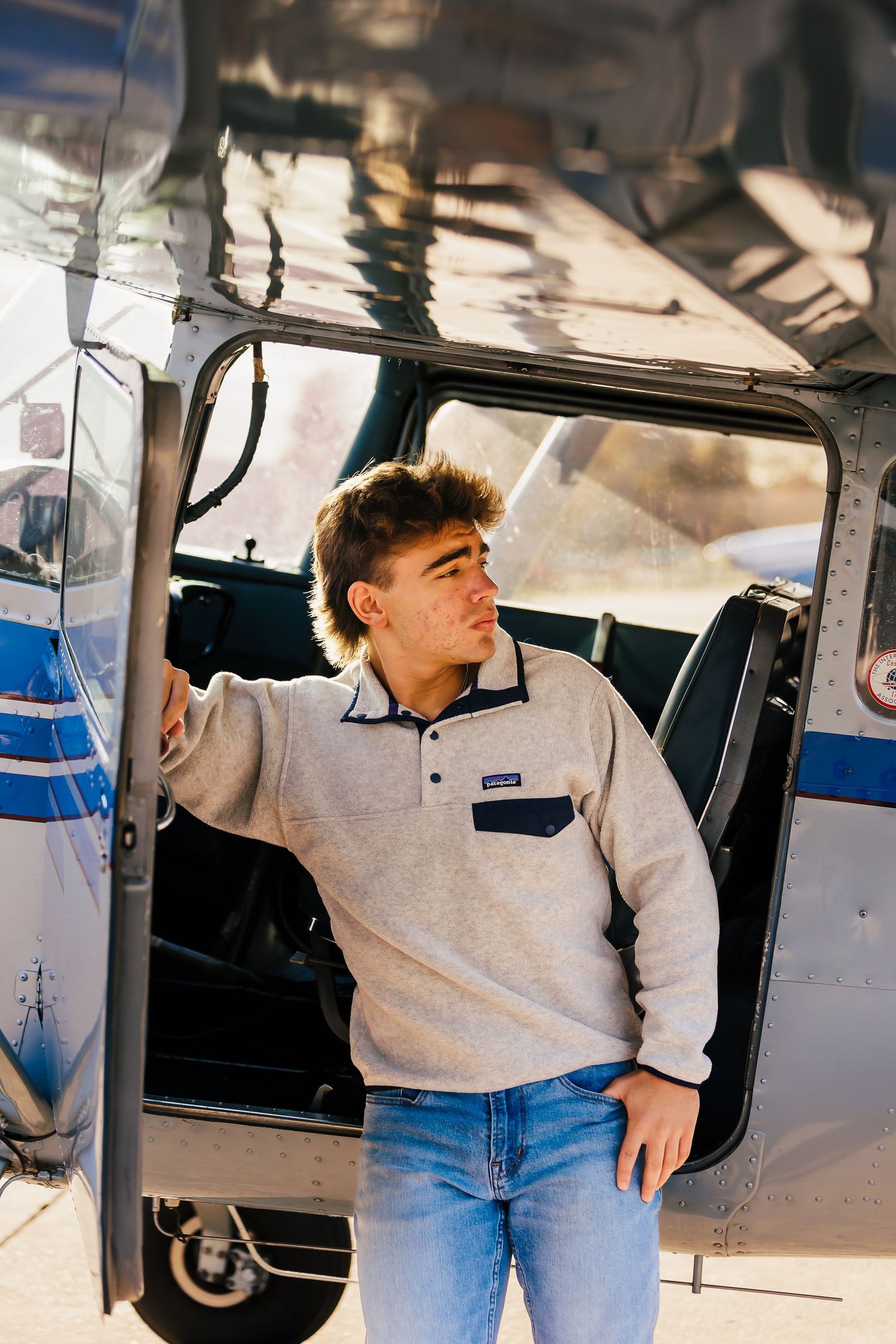 Person in casual attire standing in the doorway of a small aircraft.