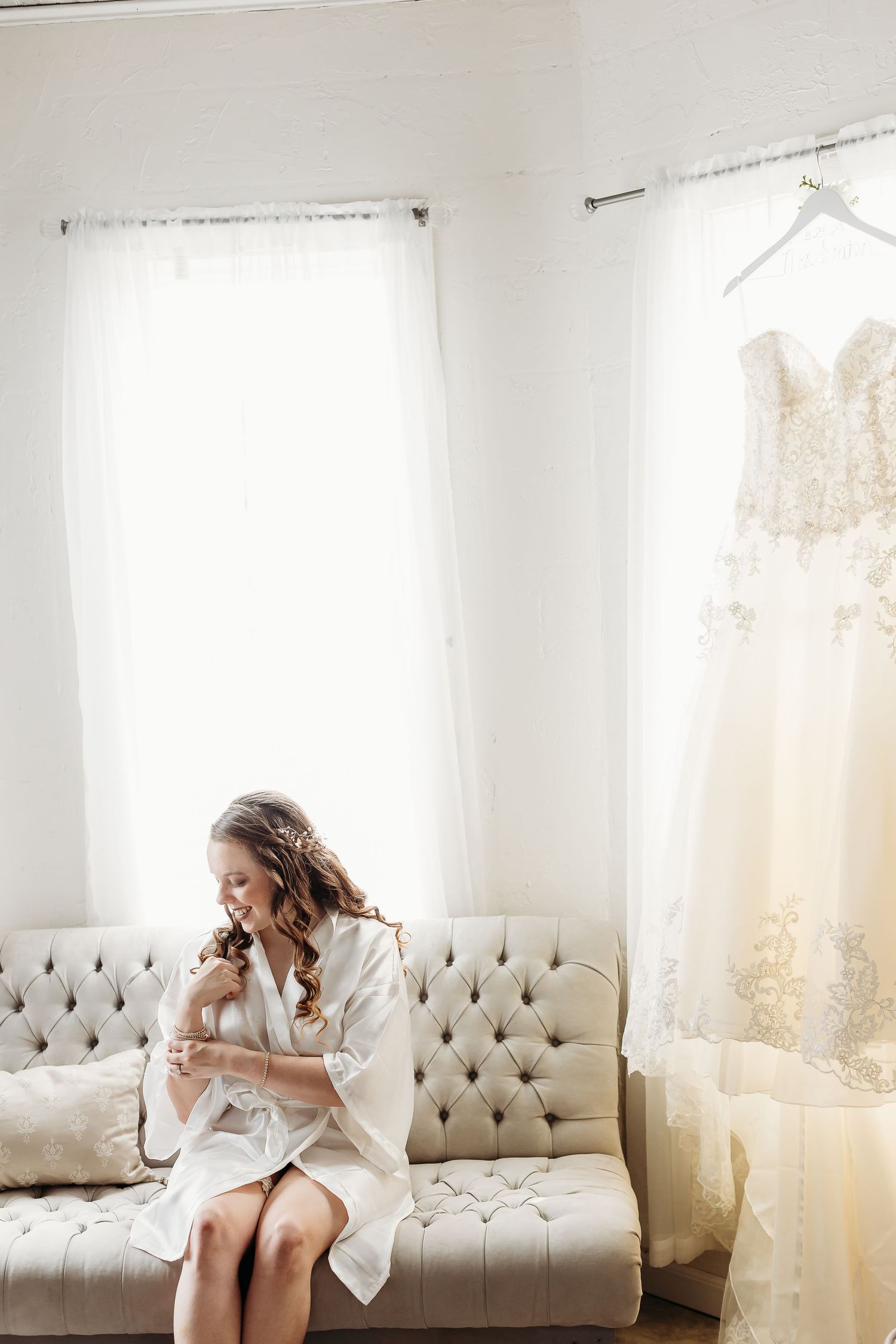 Bright white room with tufted couch and flowing curtains in morning light.