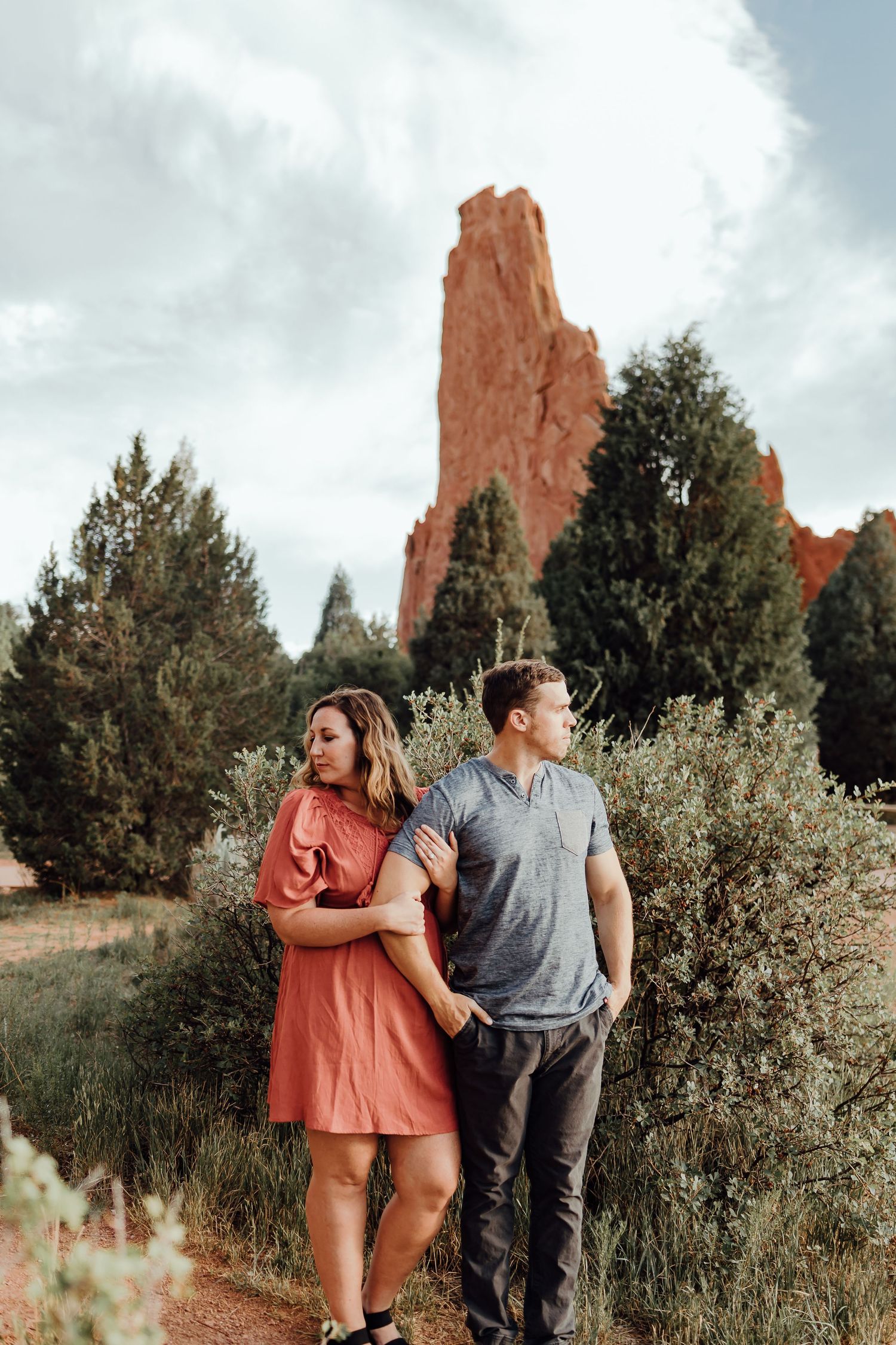 Couple walking through desert landscape with towering red rock formations.