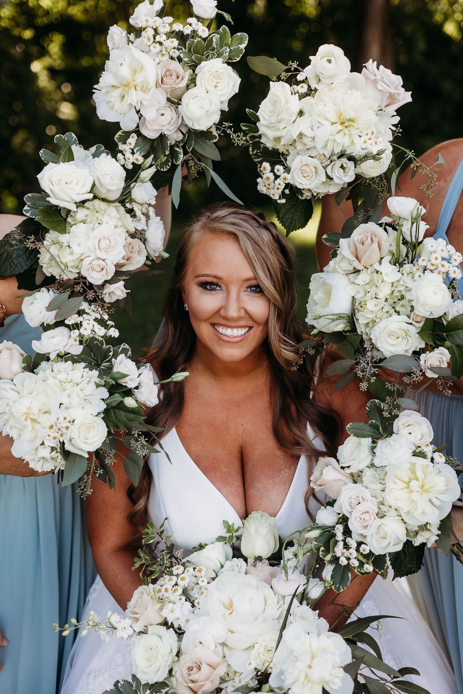 Bridal portrait surrounded by elegant white floral arrangements and greenery.
