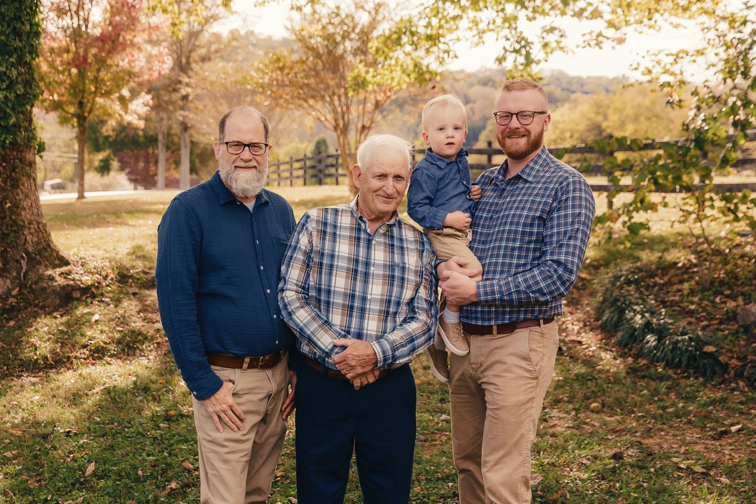 Four generations gather for a heartwarming outdoor portrait on an autumn afternoon.