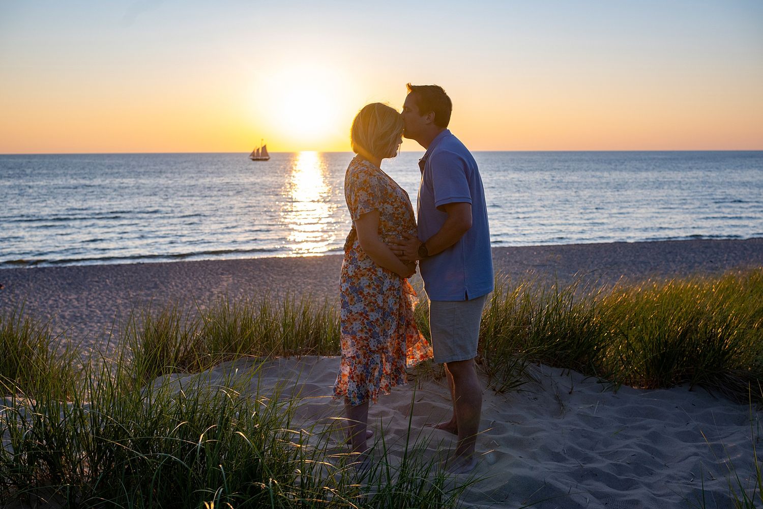 Silhouettes of a family enjoying a beautiful sunset together on a beach with tall grass.