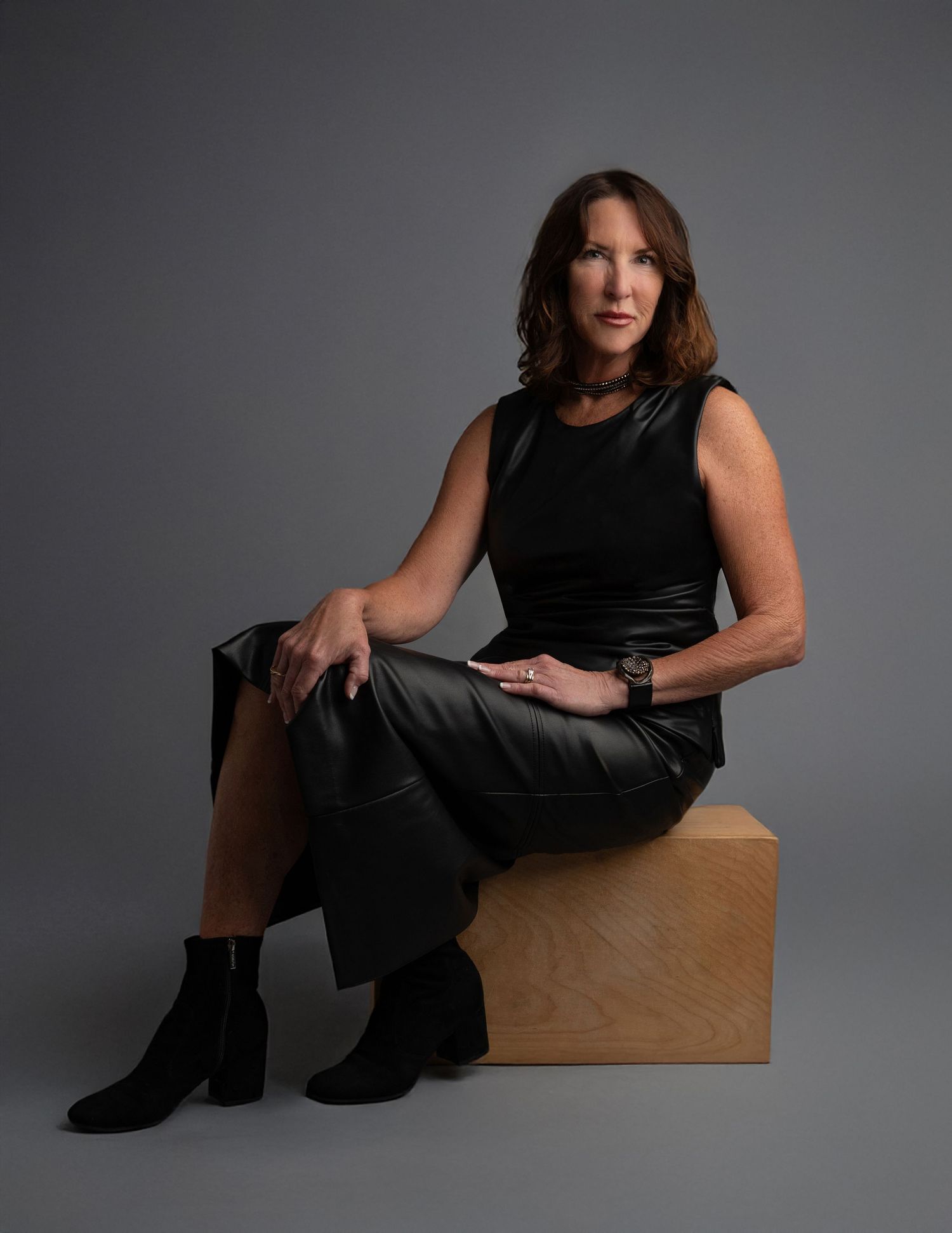 Artistic portrait series of person in black outfit posing with wooden box in studio setting.