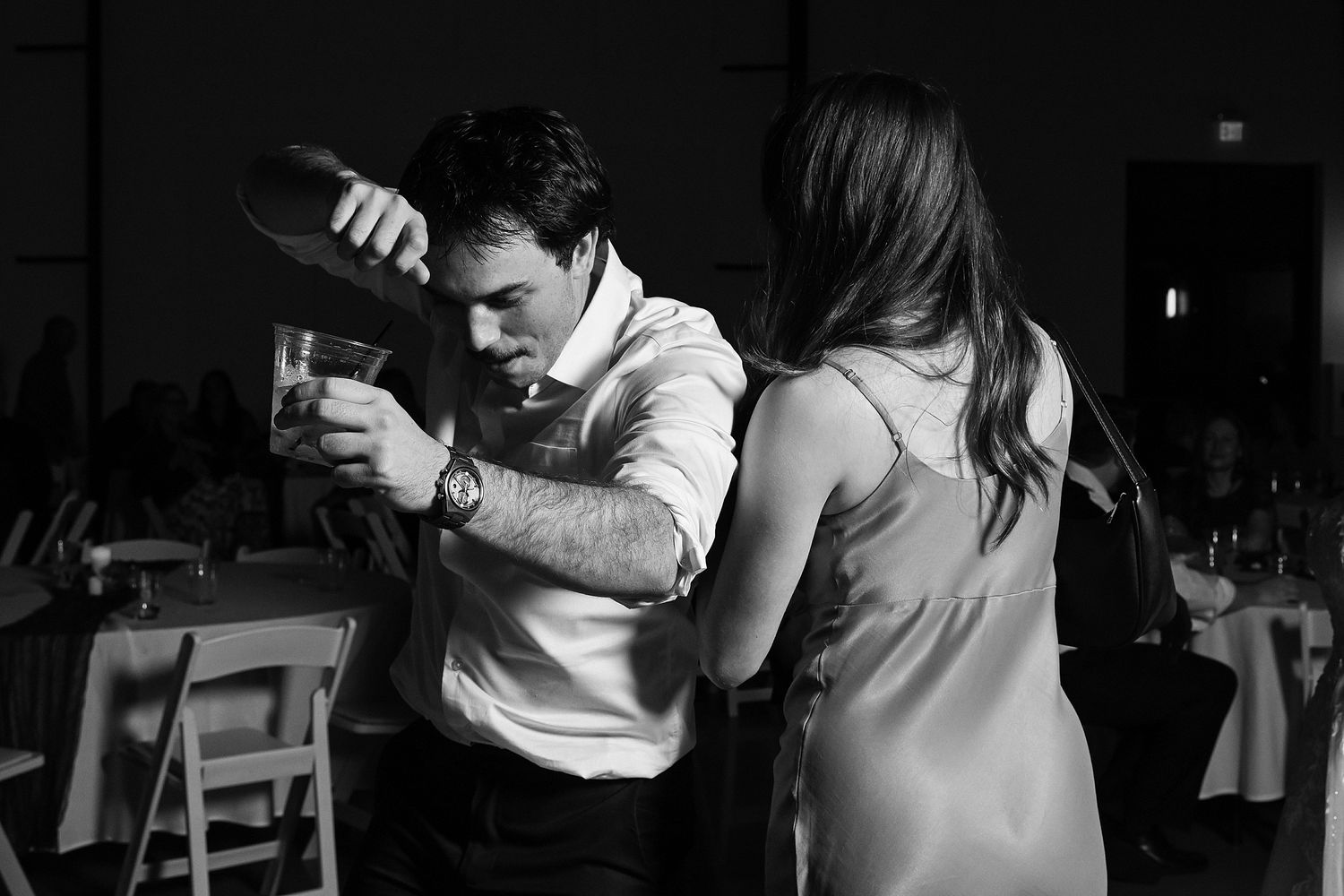 Black and white photo of man pouring drink at elegant wedding reception venue.