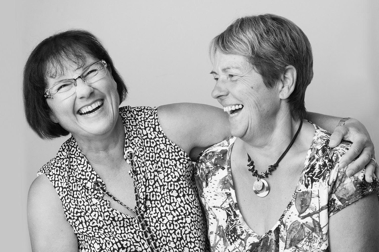 Black and white portrait of two women laughing together.