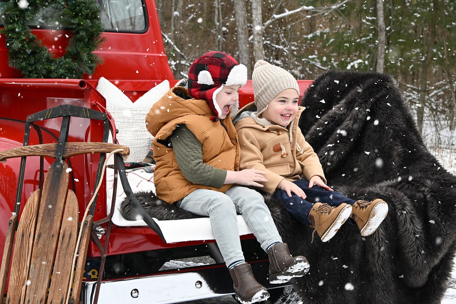 Winter family portrait session with rustic red sleigh in snowy forest.