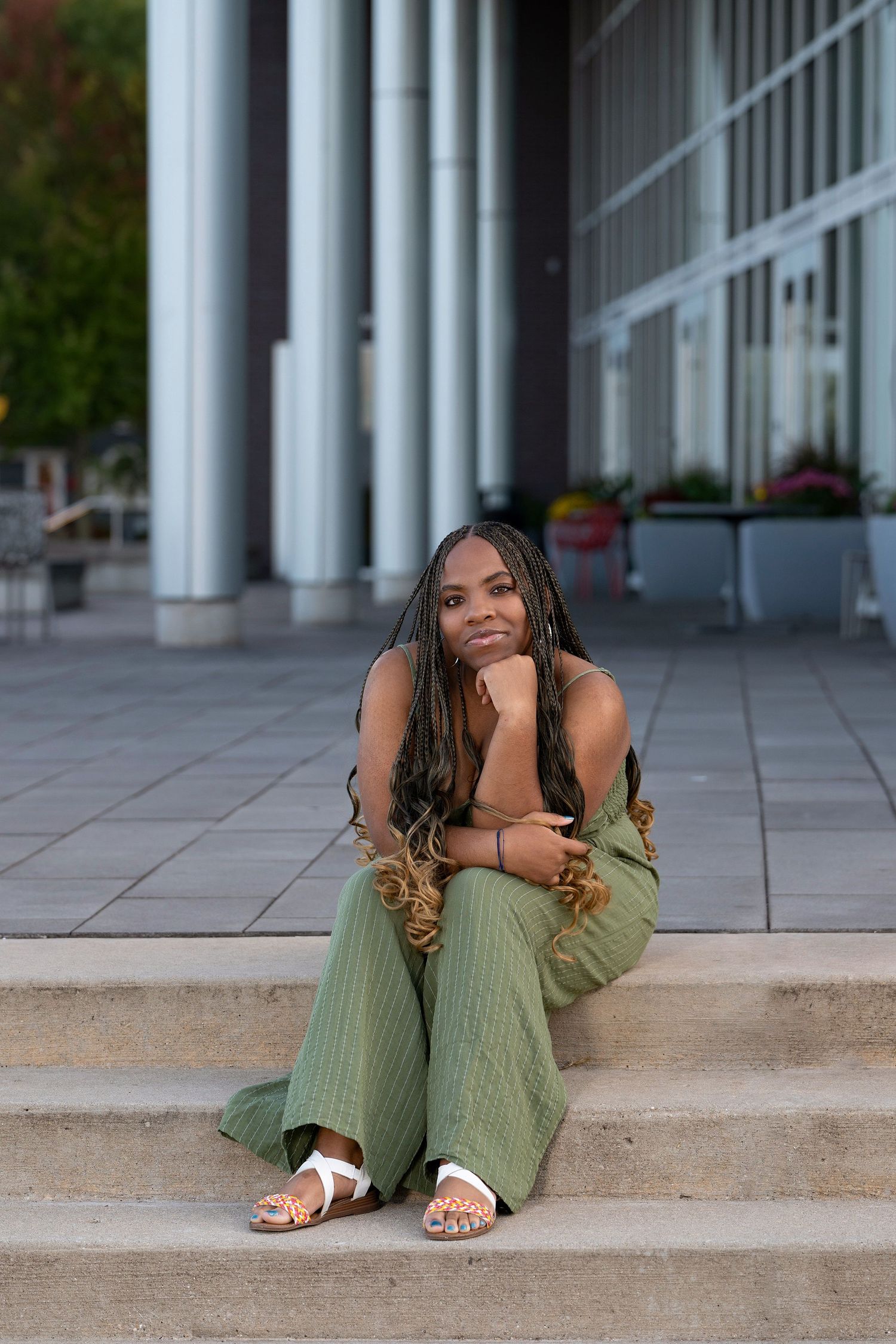 Casual portrait session featuring green outfit against modern colonnade architecture.