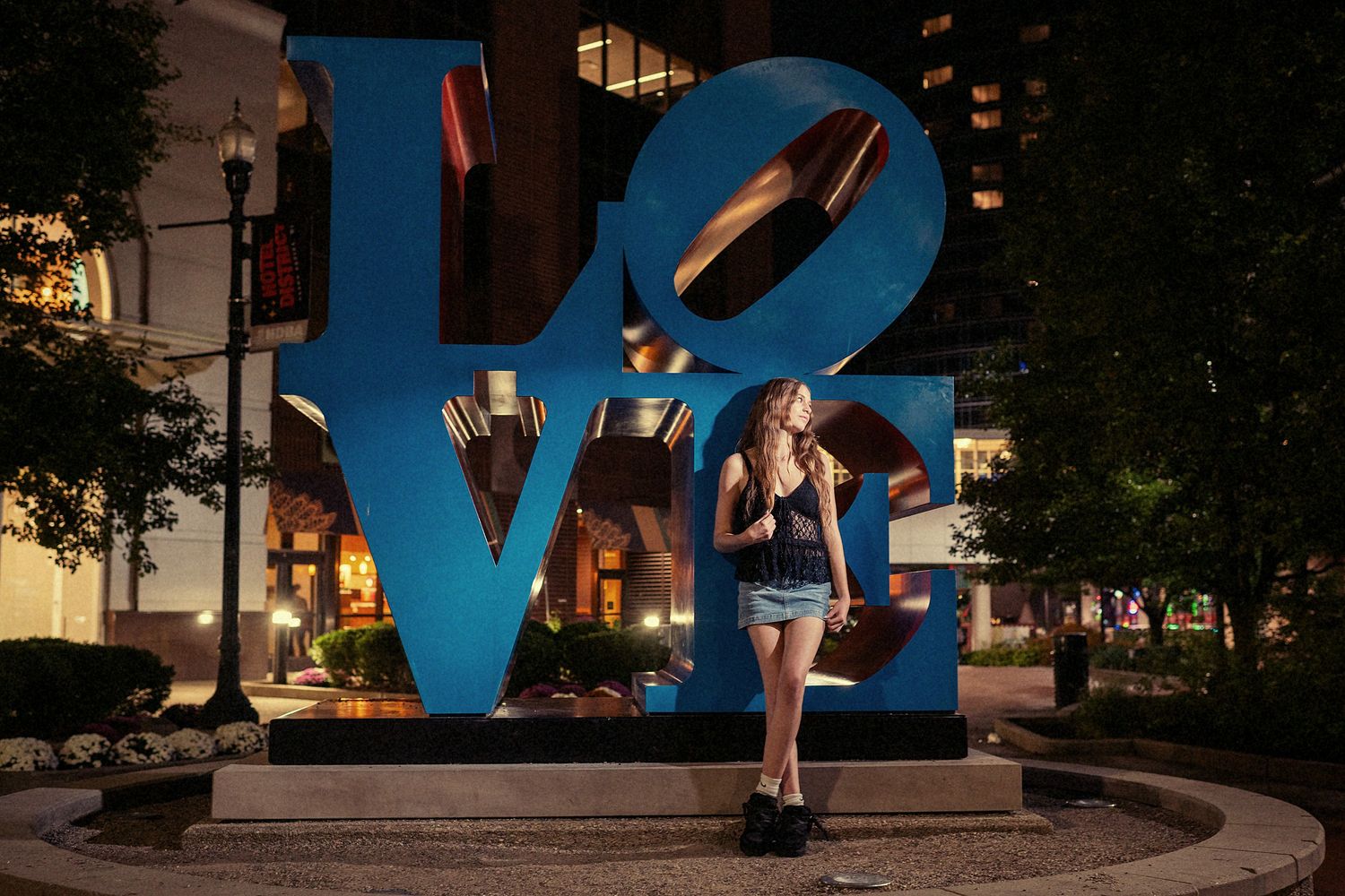 Large blue LOVE sculpture installation illuminated at night in an urban plaza.