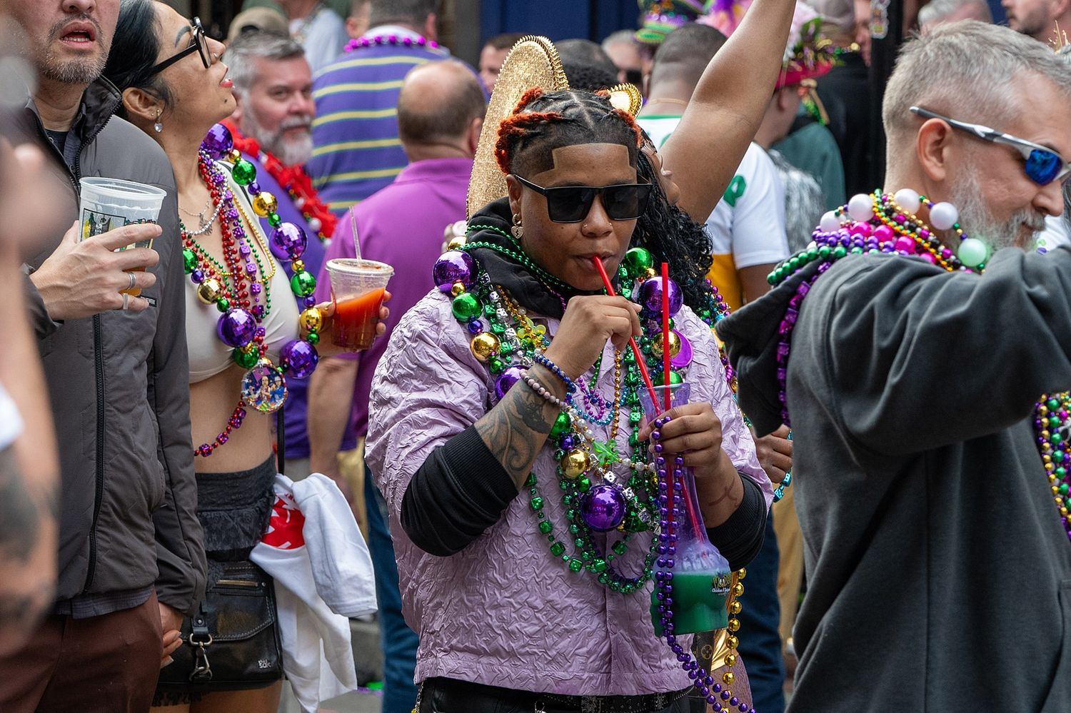 Party-goers wearing beads and sunglasses enjoy a festive outdoor celebration.