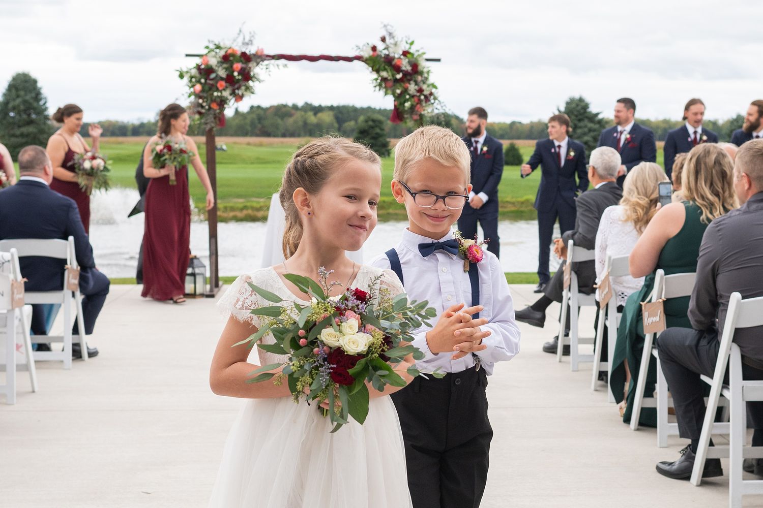 Flower girl and ring bearer smile proudly while walking back down the aisle after wedding ceremony.