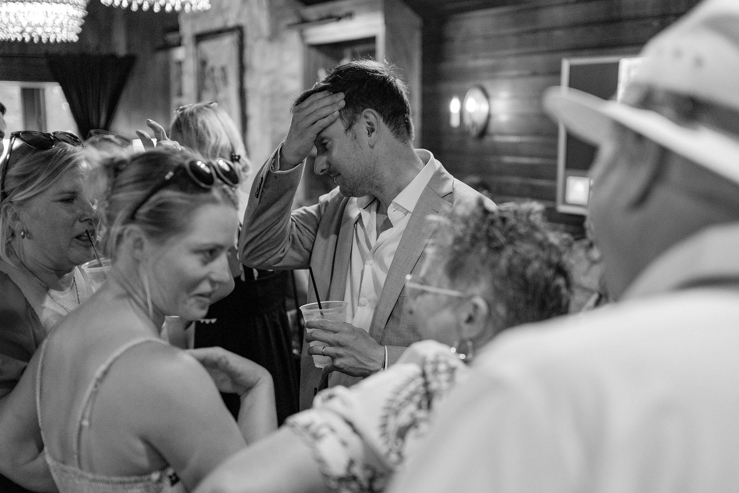Black and white photo of guests mingling at an outdoor wedding reception.