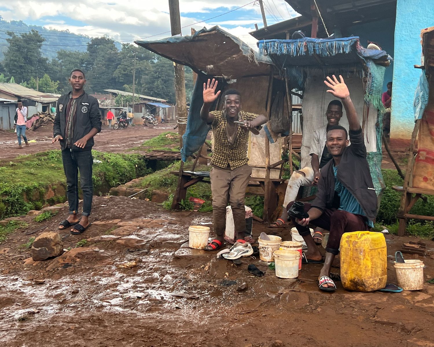 Muddy marketplace area with vendors and stalls on a rainy day.