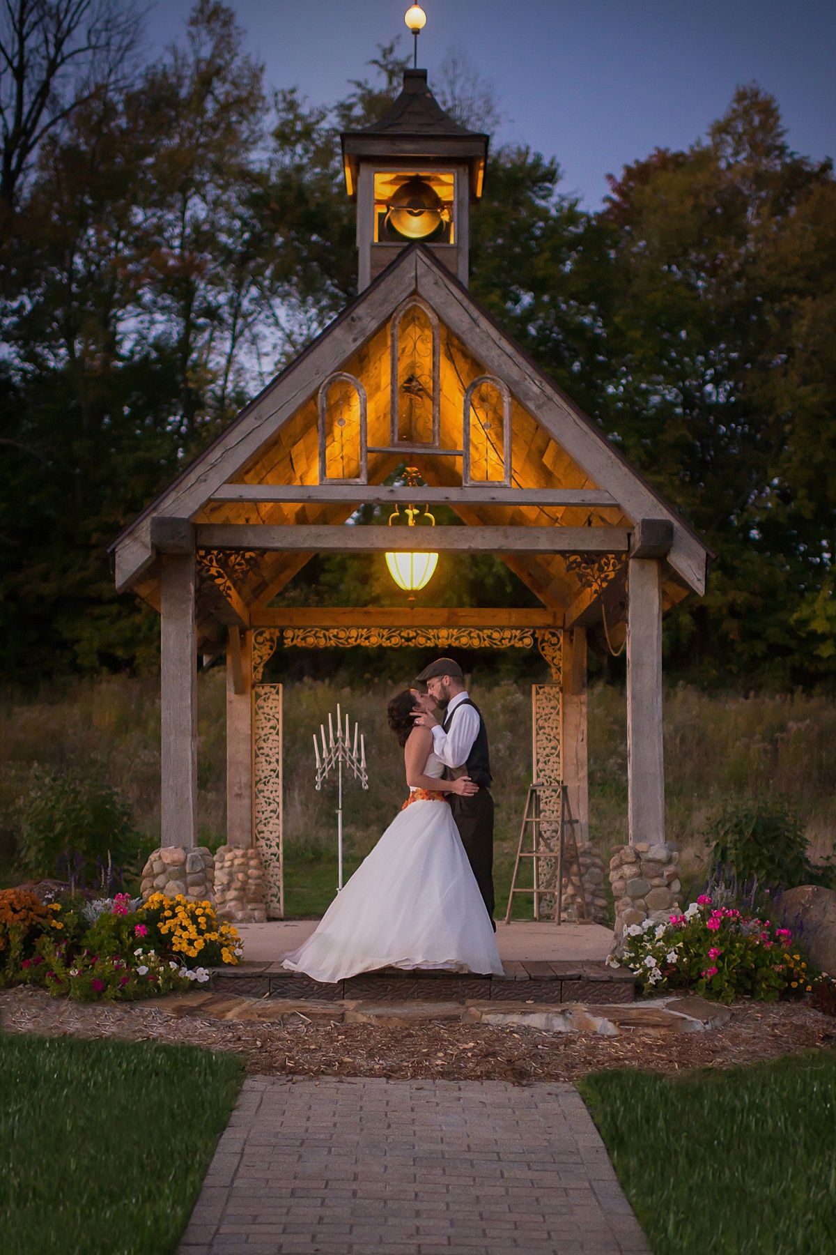 Illuminated wooden gazebo at dusk decorated for an evening wedding ceremony.