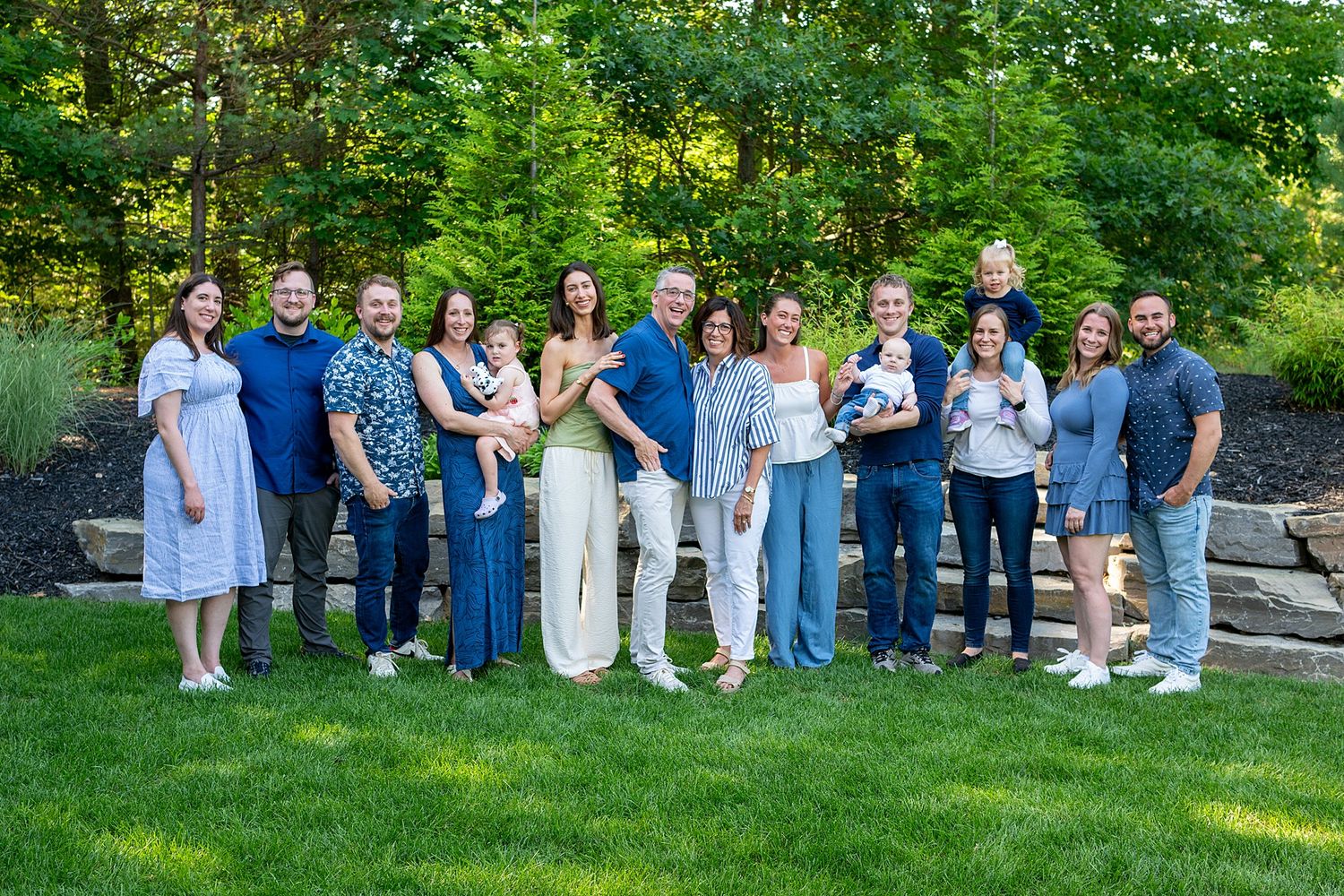 Extended family group photos arranged on grass with coordinated blue and white outfits.