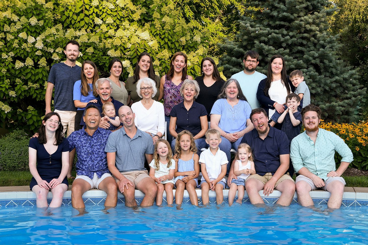 Large family gathering around a backyard swimming pool on a sunny day.