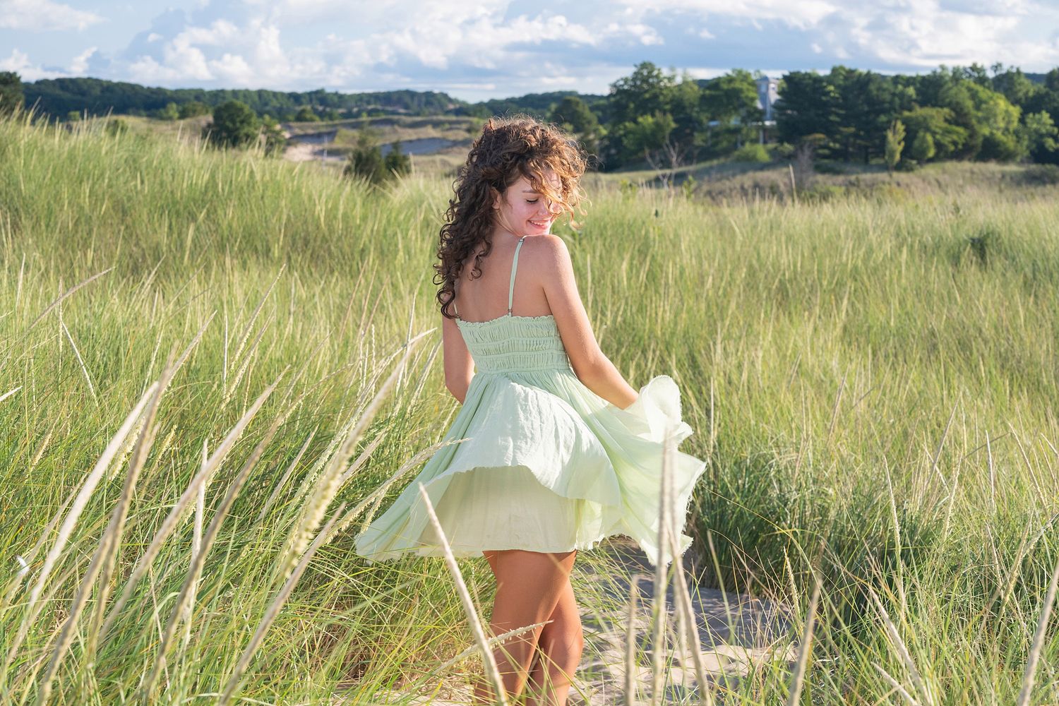 A mint green dress twirls among tall beach grass on a sunny summer day.