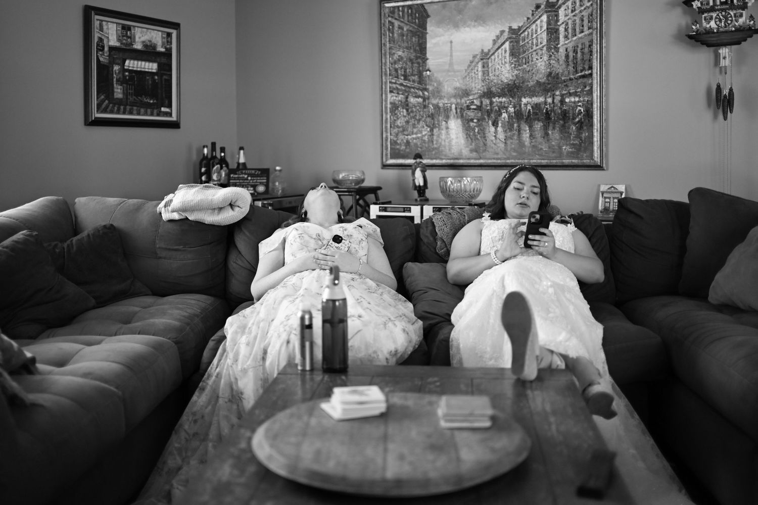 Black and white photo of wedding dress details laid out on couch with framed artwork on wall.